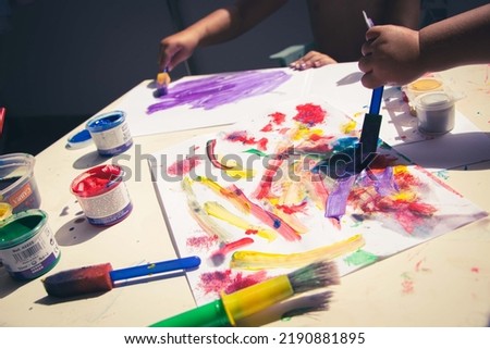 kid's drawing, painting with a brush and hands with color temperas on paper