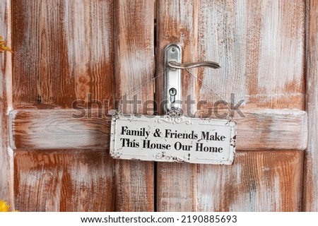 Brown wooden doors and hanging sign welcome. The part of wooden door with metal handle. 

