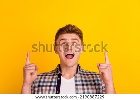 Photo of young excited guy indicate fingers empty space promo proposition isolated over yellow color background.
