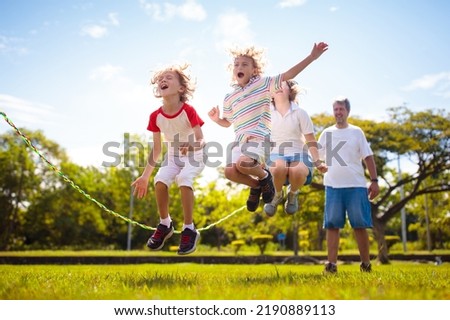 Happy kids play outdoor. Children skipping rope in sunny garden. Summer holiday fun. Group of school children playing in park playground. Healthy outdoors activity. Sport for child. Royalty-Free Stock Photo #2190889113