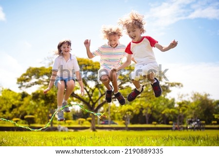 Happy kids play outdoor. Children skipping rope in sunny garden. Summer holiday fun. Group of school children playing in park playground. Healthy outdoors activity. Sport for child.