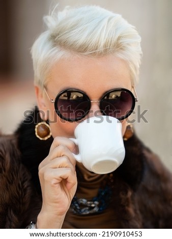 Close-up portrait of a pretty woman smiling and drinking coffee