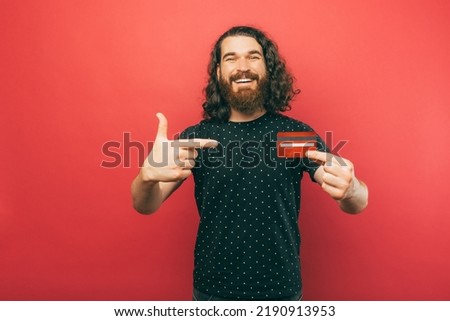 A picture of a man pointing at a credit card while smiling