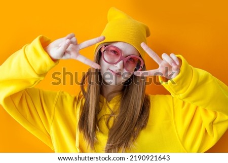 Close up fashion portrait of young pretty hipster girl wearing hats and glasses. Studio portrait of cheerful teen girl having fun and making funny faces