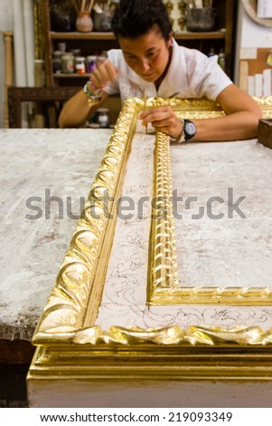 Female artisan working on a big wooden picture frame