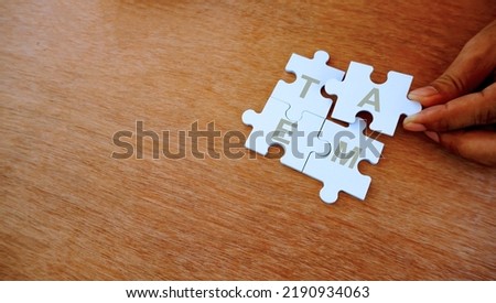 One hand put white jigsaw puzzle together. With wording of team. Concep pf team work and team player. Royalty-Free Stock Photo #2190934063