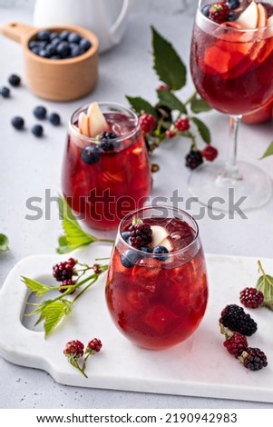 Fall berry and apple sangria in a glass with ice, refreshing fall cocktail or mocktail idea