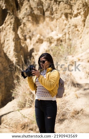 Tourist woman taking pictures with a professional camera in a canyon enjoying her vacation in peru. Concept of people, hobbies and technology.