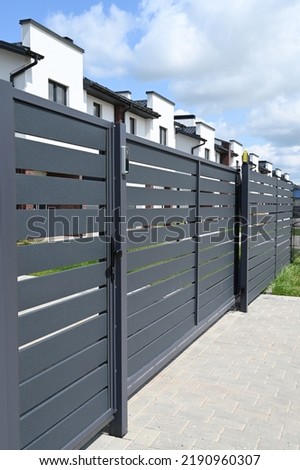 High grey fence. Modern barrier aluminum slats. Modern stone fence with metal shutters. Royalty-Free Stock Photo #2190960307