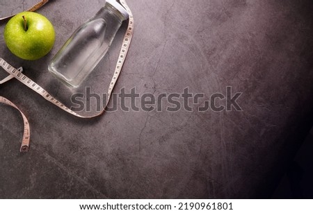 Fitness concept with water and apple tape measure
