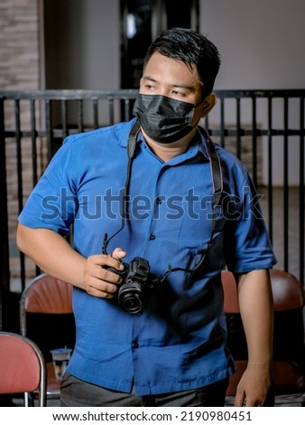 portrait of freelance photographer with holding a mirrorless camera  