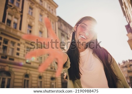 Portrait of charming lovely cheerful girl raise arm camera you toothy smile enjoy pastime outside