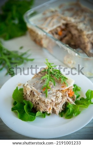 jellied meat with greens and vegetables in a plate on a wooden table