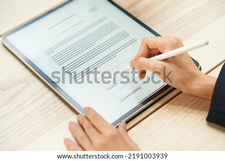 A woman signing using a tablet PC and stylus pen