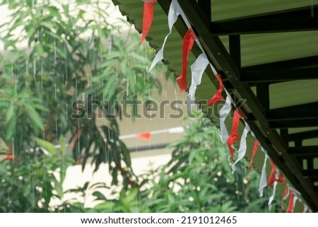 Red and white triangular hanging on the rope with rainy day and tree background.