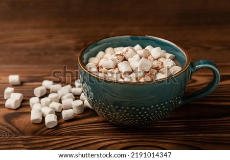 Cup of tasty cocoa drink and marshmallows in blue cup.Spices and marshmallows for winter drinks on brown texture table.Winter hot drink.Hot chocolate with marshmallow and spices.Copy space.