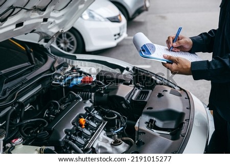 Mechanic check list to the clipboard insurance with inspecting car at garage workshop, Car auto services and maintenance check concept. Royalty-Free Stock Photo #2191015277
