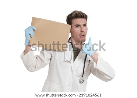 Young caucasian male doctor thumbs up pointing at a board. Isolated over white background.