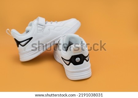 White sports shoes for children lying on top of each other, rear view, stylized leather sneakers in black and white colors, mock up, copy space Royalty-Free Stock Photo #2191038031