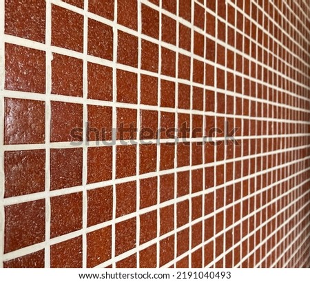 Wall coated with red glass tiles in perspective. Selective focus.