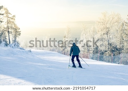 skier descends the track, view from the back, forest landscape of highlands in winter. outdoor activities in winter