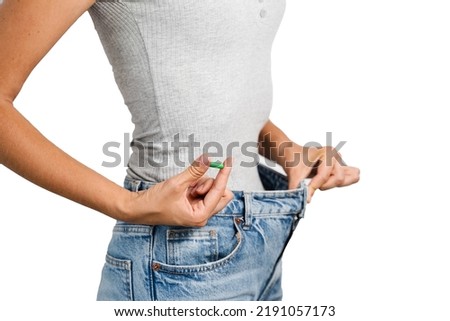 Woman with weight loss pills showing result of diet on white background. Weight loss with biologically active supplements