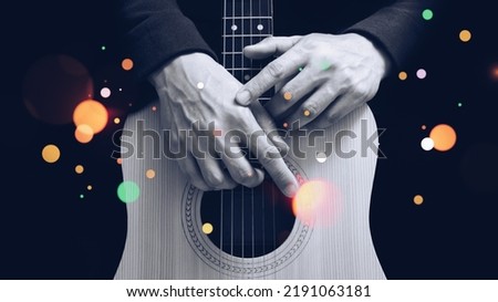 black and white male guitarist hands on acoustic guitar body with colorful bokeh, isolated on black. music background