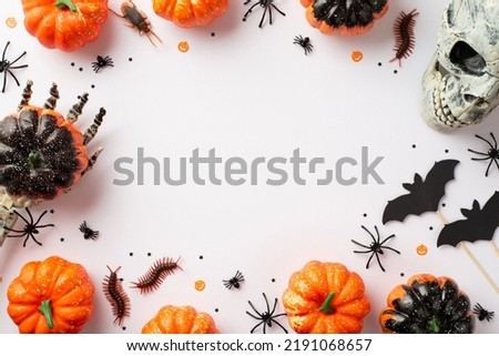Halloween party concept. Top view photo of skeleton hands holding pumpkins skull bat silhouettes spiders cockroach centipedes and confetti on isolated white background with copyspace in the middle