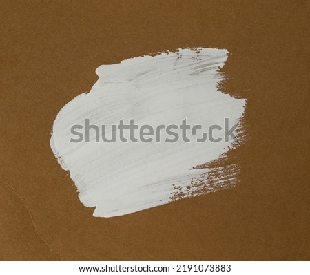 An image of a rough brushstroke on cardboard. A spot of white paint on craft paper. background with space for text.
