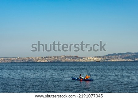 Two women kayaking on İzmir Bay, Mavisehir, Karsiyaka. Canoeing in the bay against the city of Izmir. Canoe lessons and training. 