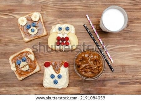 Funny cute bear,monkey,fox,owl faces sandwich toast bread with peanut butter,banana,blueberry,raspberry,milk. Kids childrens baby's sweet dessert healthy breakfast lunch food art,close up,top view.