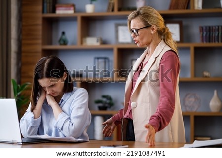 Angry female boss scolding scared office worker. Demanding manager leader is annoyed at laziness and mistakes in work of employee. Authoritarian leadership, abuse of power, malfeasance in office Royalty-Free Stock Photo #2191087491