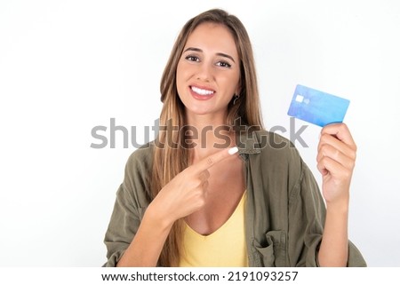 Photo portrait of young beautiful woman wearing green overshirt over white background doing purchase with pointing finger credit bank card