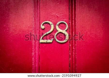 House number 28 on a dark rd wooden front door