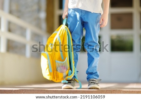 Little student with a backpack on the steps of the stairs of school building. Close-up of child legs, hands and schoolbag of boy standing on staircase of schoolhouse. Kids back to school concept. Royalty-Free Stock Photo #2191106059
