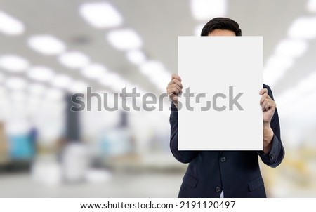 Business man showing blank white paper at industrial warehouse. 