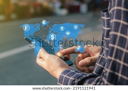  
Man holding a smartphone to do online financial transactions for overseas spending. Work in the global financial market via mobile device. money transfer and exchange, global currency concepts.
  Royalty-Free Stock Photo #2191121941