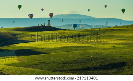 Hot air balloon flying over green field landscape at Cappadocia Turkey Royalty-Free Stock Photo #219113401
