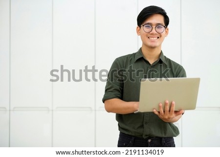 Smiling asian business man online working on laptop at home office. Young boy asian student or remote teacher using computer online studying, virtual training, watching online education webinar. Royalty-Free Stock Photo #2191134019