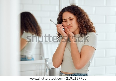 Toothache, pain and sensitive teeth with a woman brushing her teeth in a bathroom at home. Young female with a cavity suffering from discomfort during dental hygiene routine. Lady with a sore mouth Royalty-Free Stock Photo #2191139955