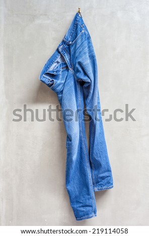 Unwashed blue jeans is hanging on the exposed concrete wall in bathroom.