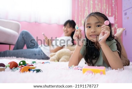 Loving young Asian mother and little daughter playing together on carpet floor, building towers from toy construction bricks, talking, enjoying leisure, playtime, creative game. Motherhood concept. Royalty-Free Stock Photo #2191178727