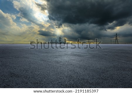Empty asphalt road ground and high voltage power towers on cloudy day Royalty-Free Stock Photo #2191185397