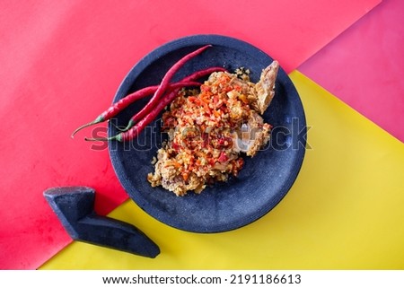 Indonesian Food Ayam Geprek. Fried Chicken Smashed with Spicy Chili using Stone Food Smasher.  Royalty-Free Stock Photo #2191186613