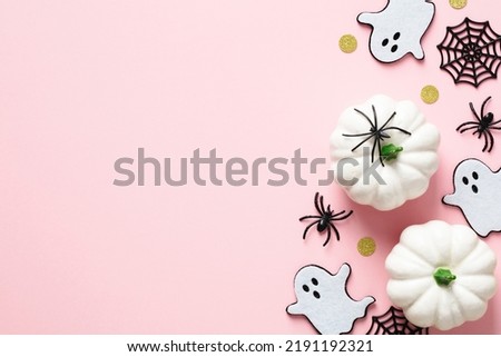 Cute Halloween decorations on pastel pink background. Flat lay ghosts, spiders, webs, white pumpkins. Halloween greeting card template with copy space.