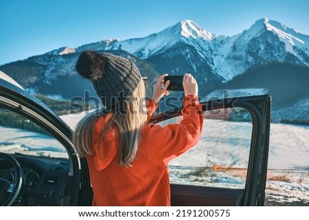 Woman traveling exploring, enjoying the view of the mountains, landscape, lifestyle concept winter vacation outdoors.
Female standing near the car in sunny day