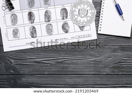 Paper sheet with finger prints, seal of FBI and notebook on dark wooden background