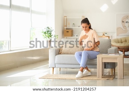Young woman suffering from breast pain at home Royalty-Free Stock Photo #2191204257