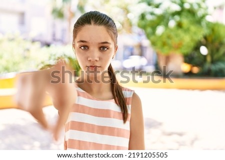 Young teenager girl outdoors on a sunny day pointing with finger to the camera and to you, confident gesture looking serious 