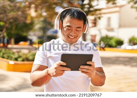 Young chinese man smiling confident watching video at park